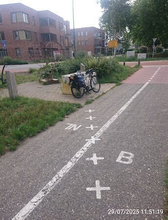 Fahrrad vor einer Bank, die Bank wird von einer Bodenmarkierung gequeert