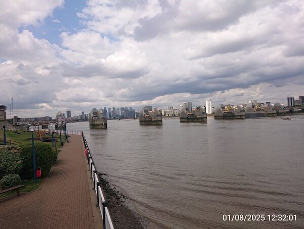 Fluß mit Wehranlage und zahlreiche Hochhäuse dahinter