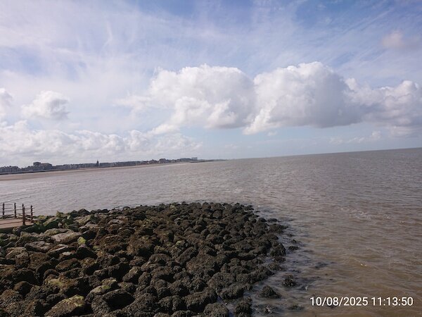 Blick entlang einer Meeresküste am Ende ein großes Gebäude