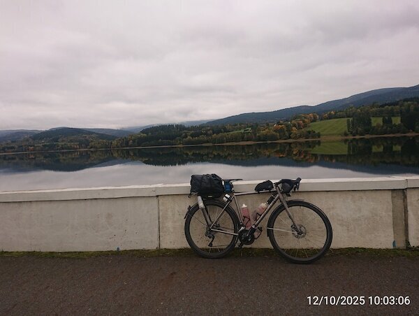 Fahrrad vor See in dem sich Landschaft spiegelt